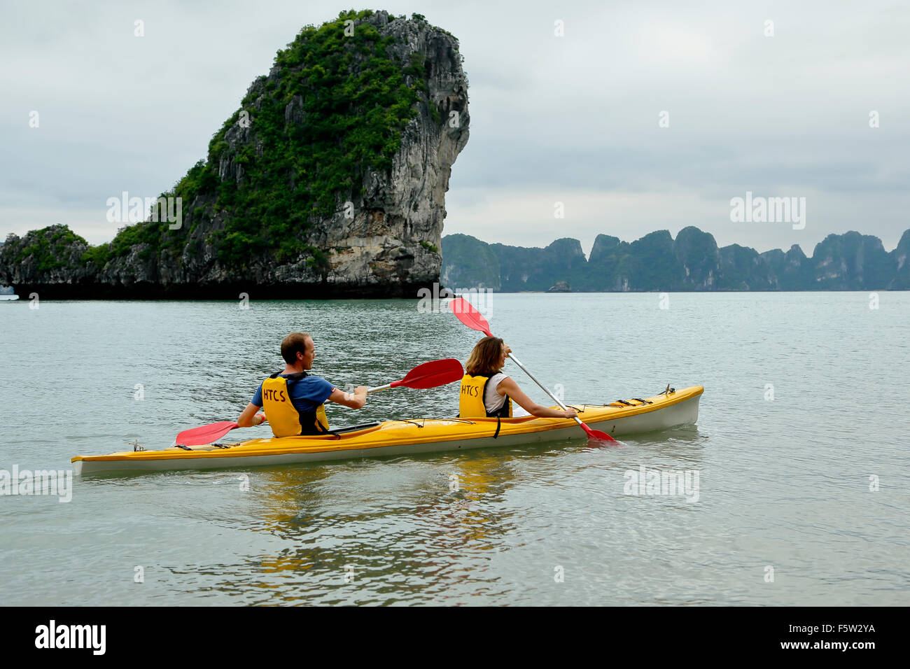 Couple kayaking and limestone (karst) mound, Ha Long Bay, Bai Tu Long Sector, near Ha Long, Vietnam Stock Photo