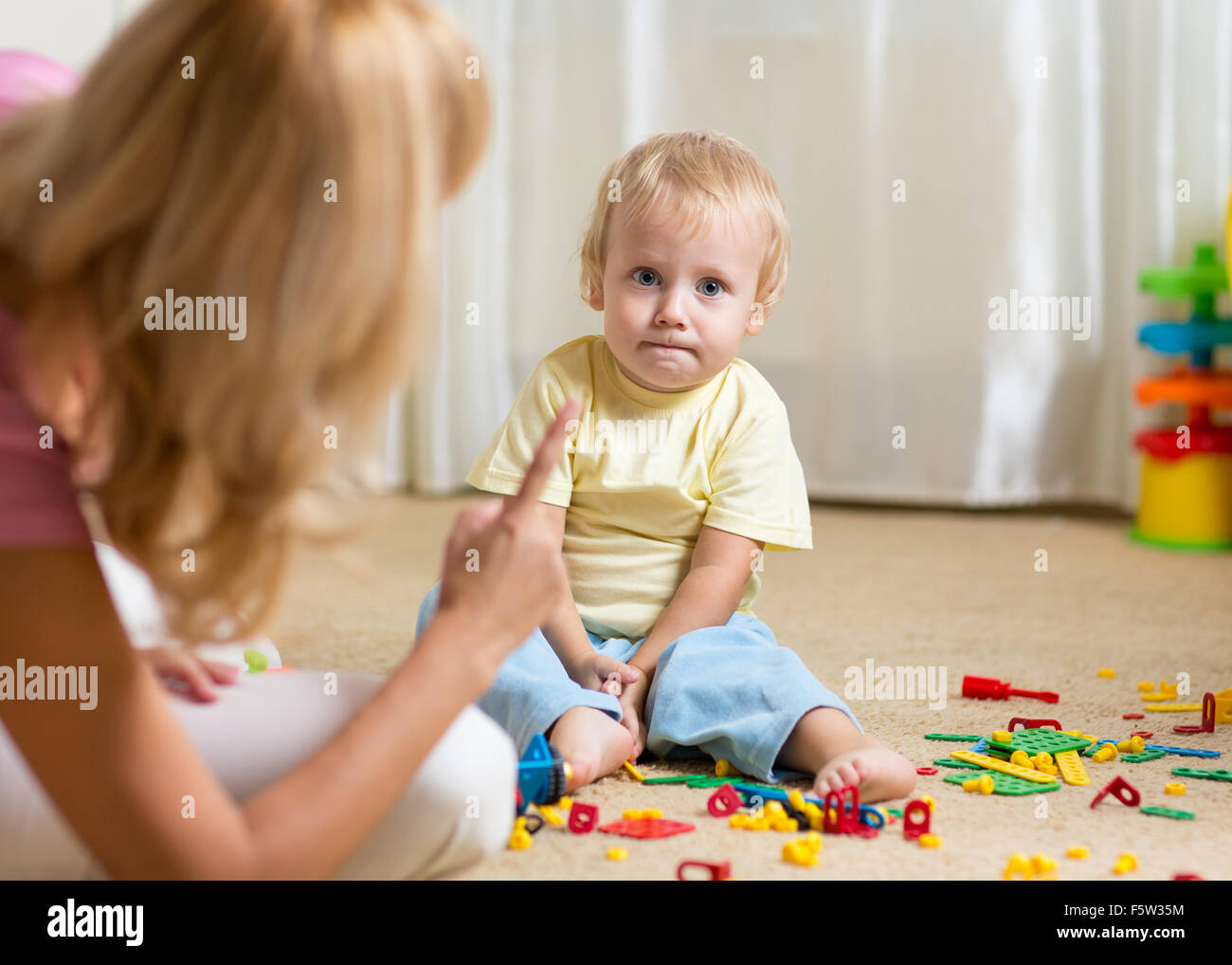 Mother berating her little kid in jest at home Stock Photo