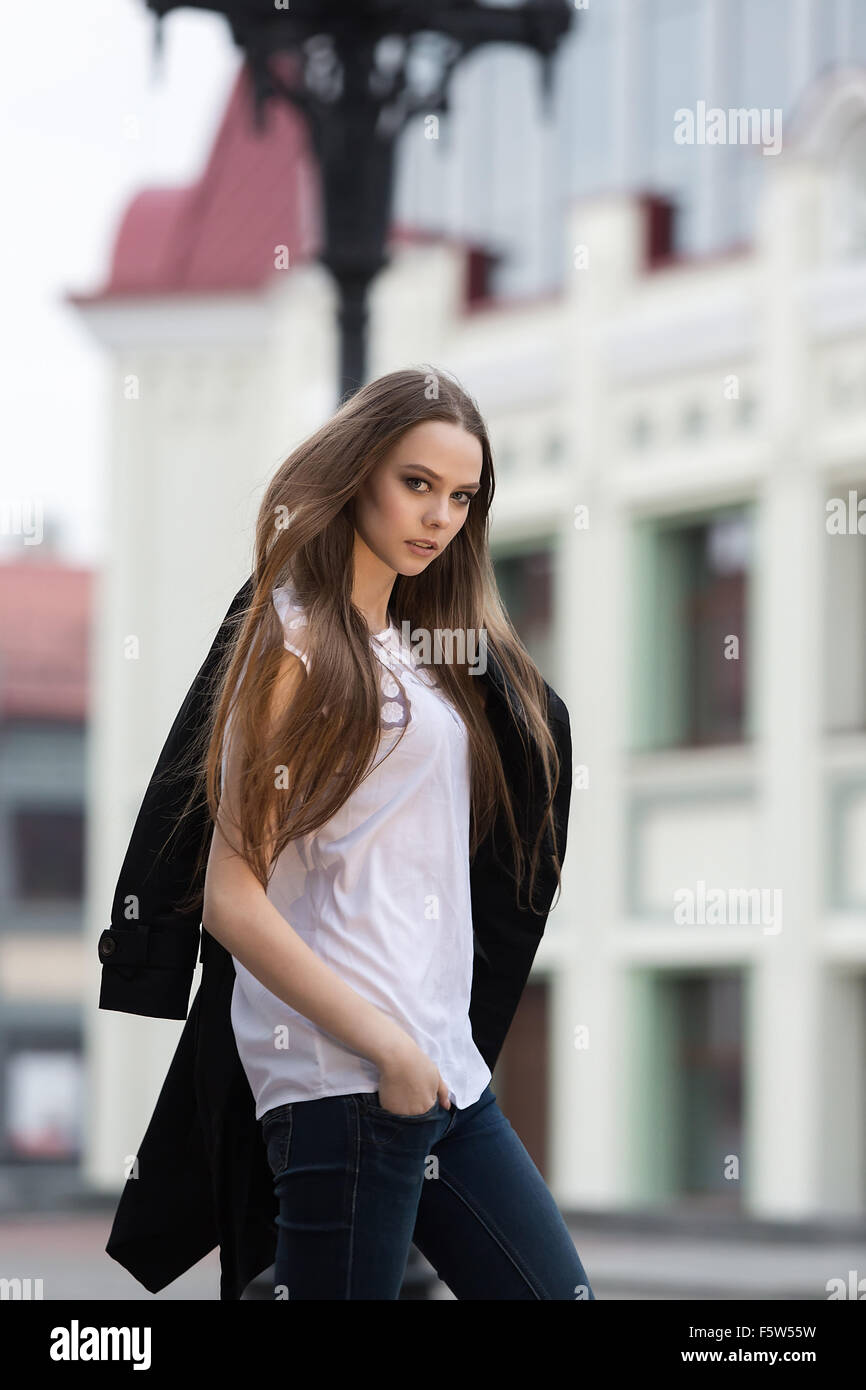 beautiful girl walks on the square in the city with a black coat Stock Photo