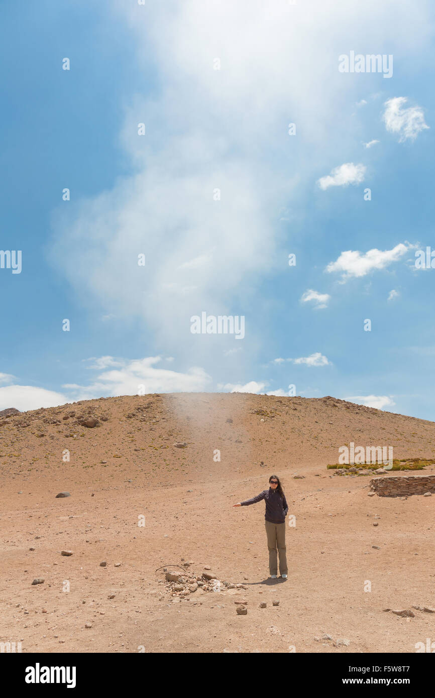 Woman touches hot steam at Sol de Manana geothermal field in Bolivia Stock Photo