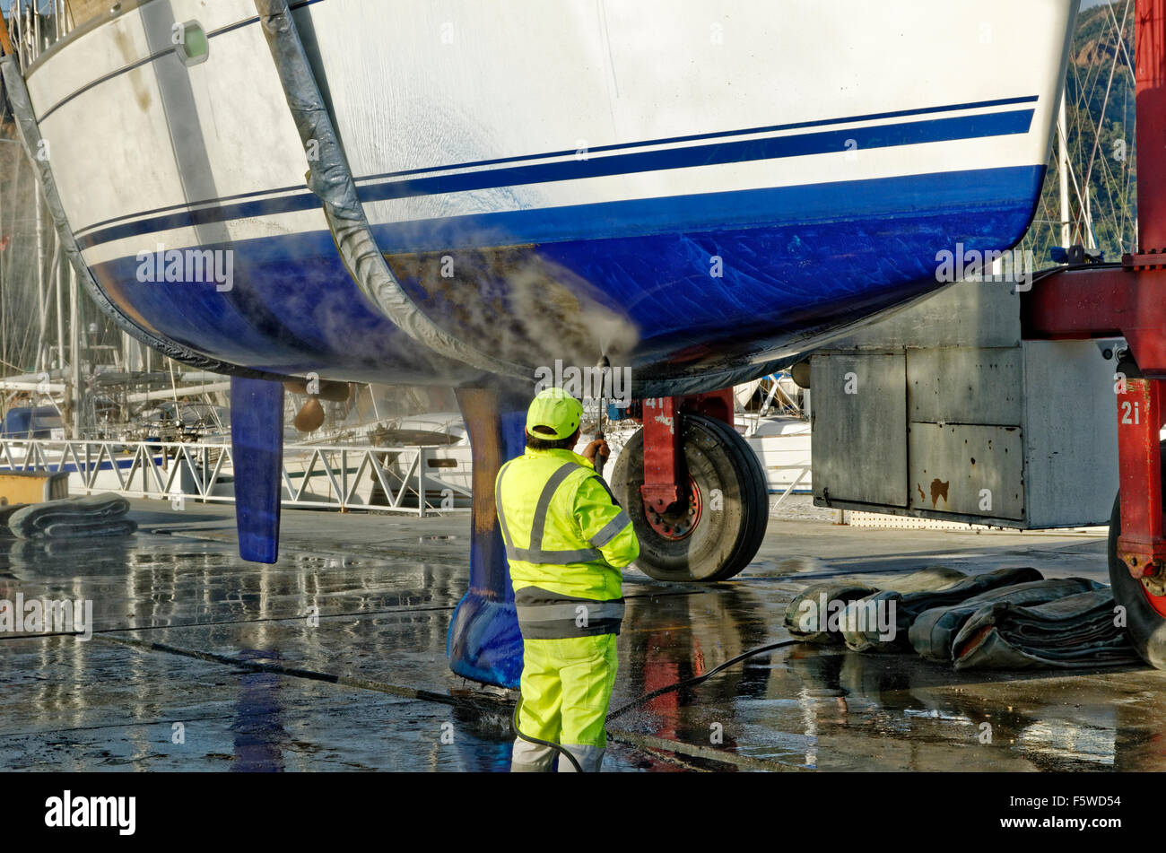 Cruising yacht being lifted and jet-washed to remove marine fouling. Stock Photo