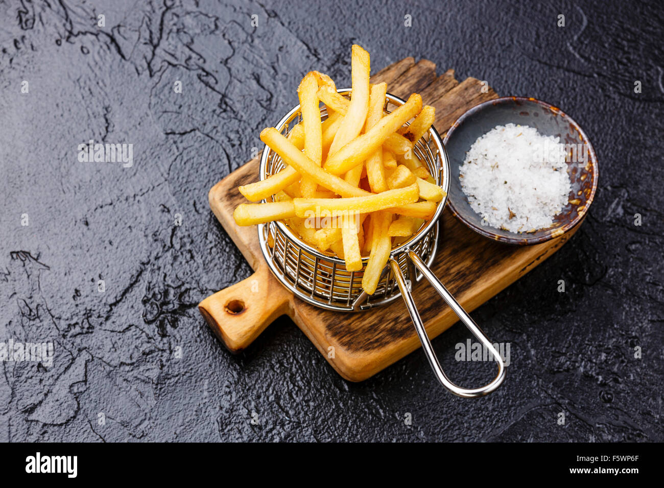 French fries in basket for serving on black stone background Stock