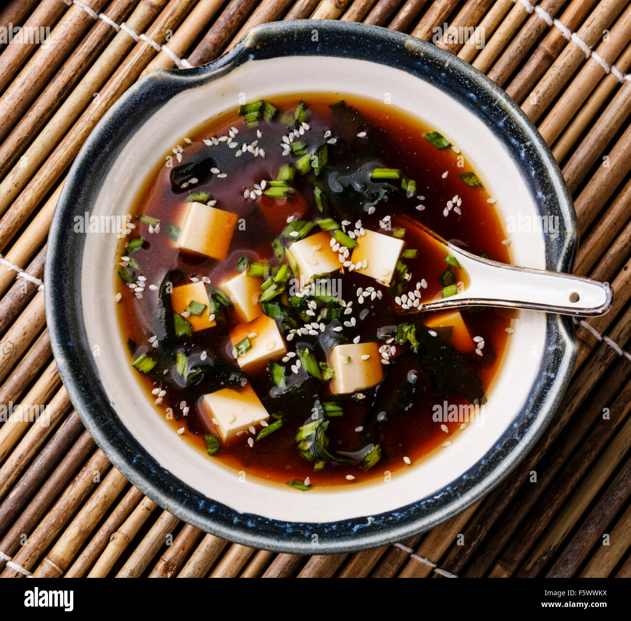 Miso Soup with tofu, seaweed and sesame in bowl on bamboo background Stock Photo