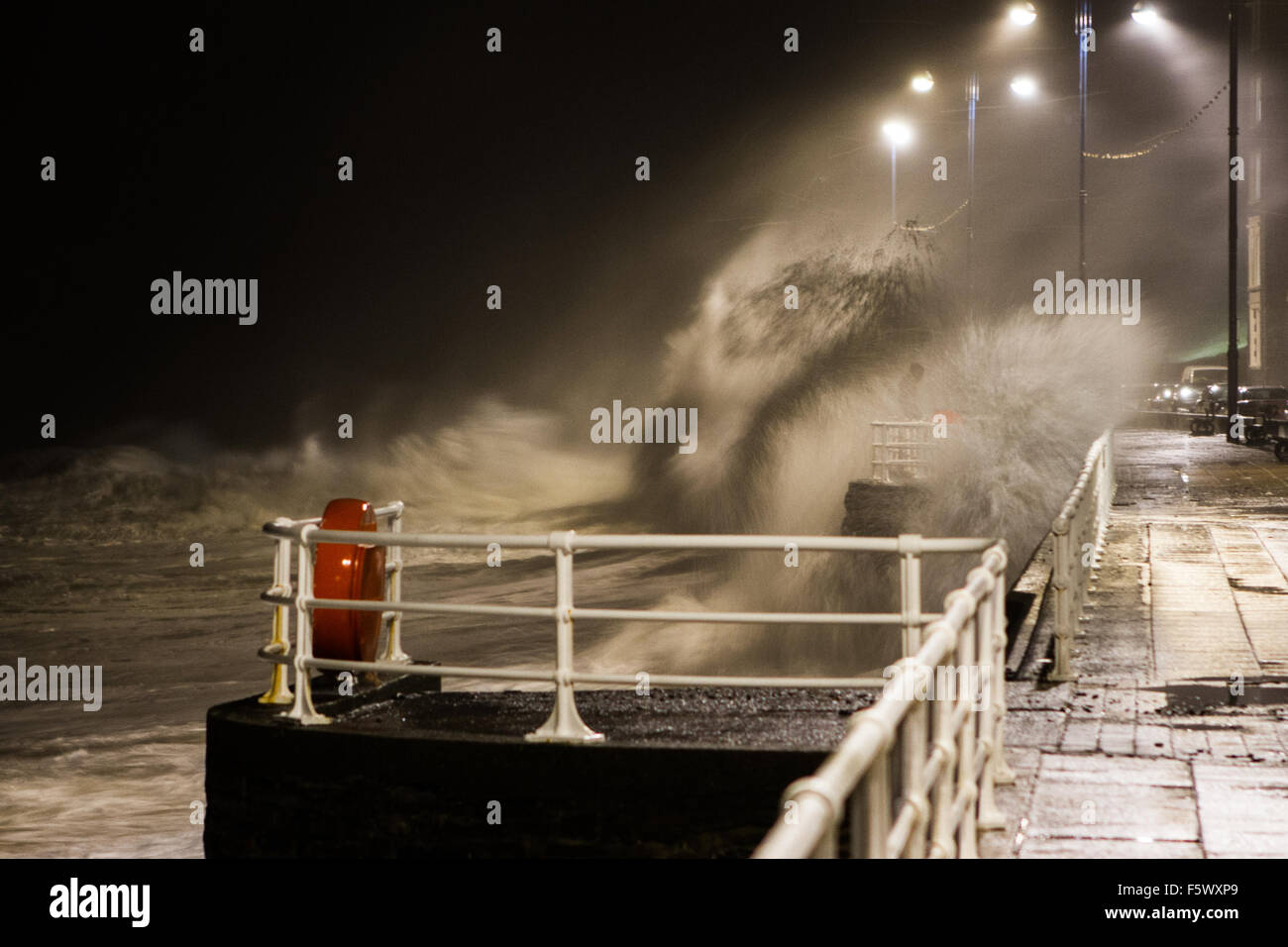 Big waves battering Aberystwyth promenade as man holds onto railings waiting to get submerged by the next wave Aberystwyth Stock Photo
