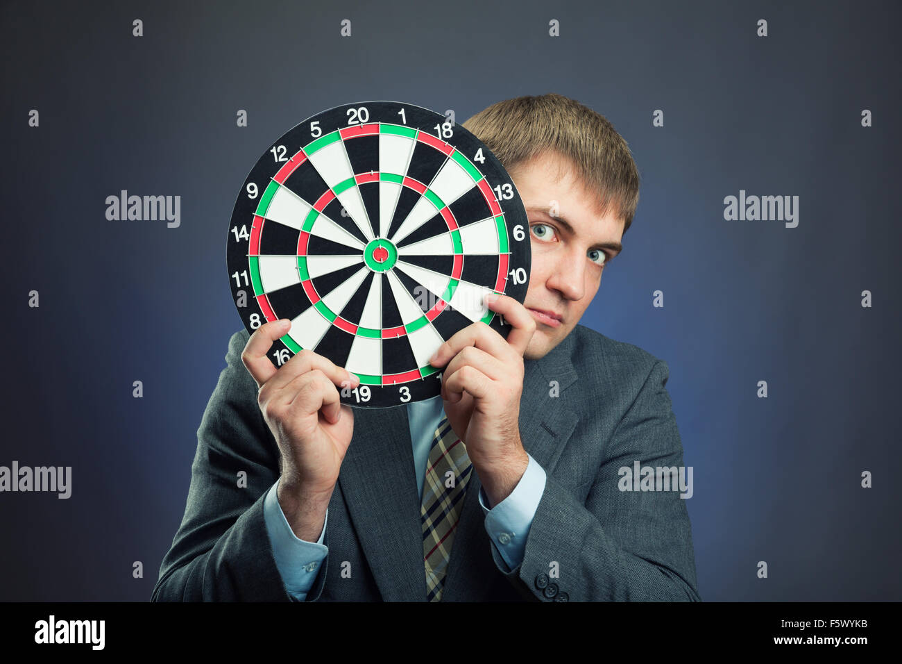 Businessman holding darts board in his hands isolated on gray Stock