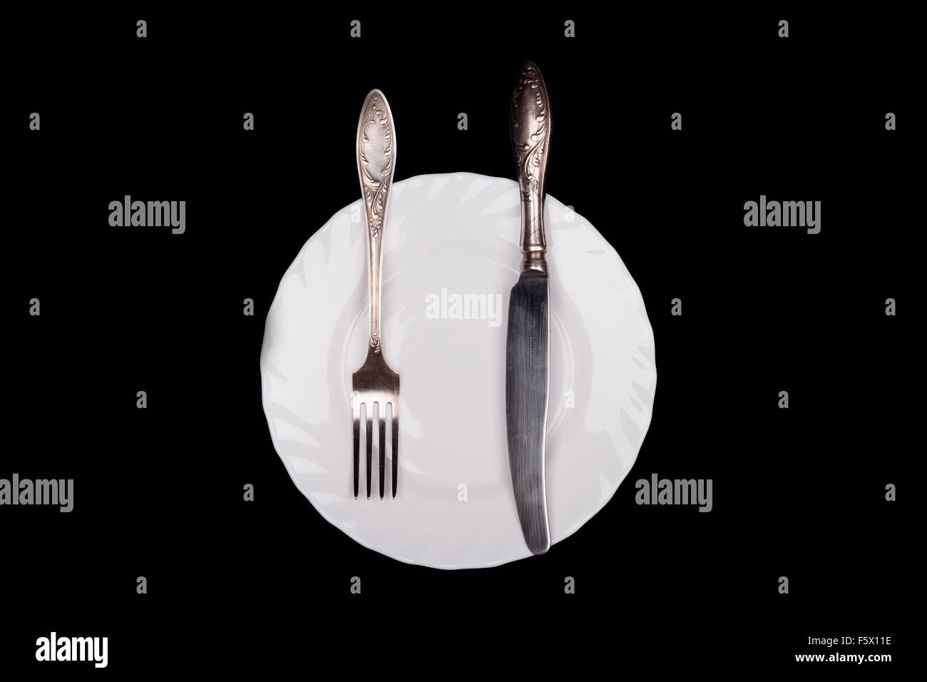 Etiquette sign. Plate, fork, knife top view isolated on black Stock