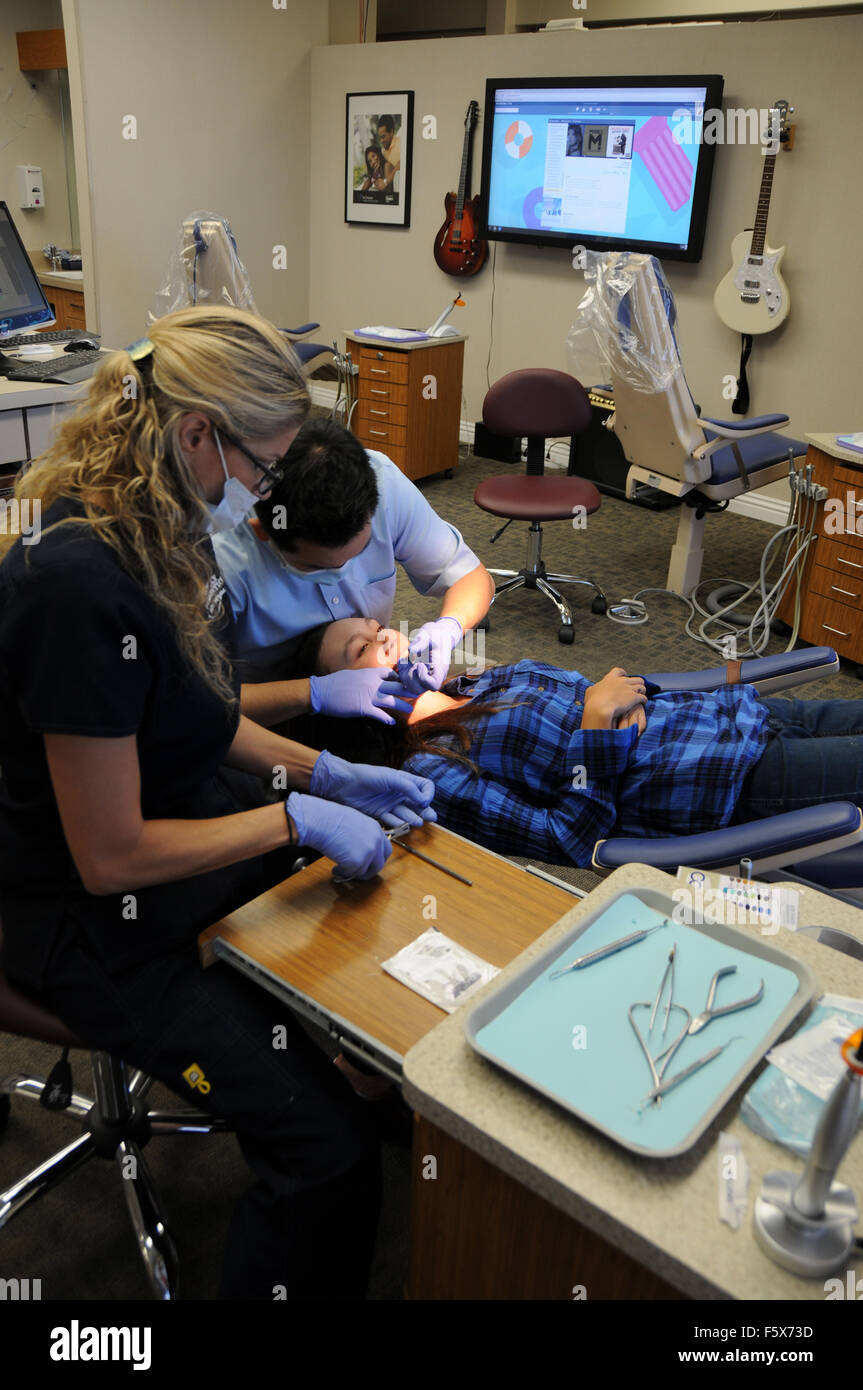 An orthodontist is a type of dentist who specializes in straightening crooked teeth. Here with assistant and patient in office. Stock Photo