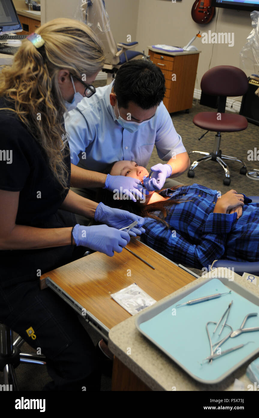 An orthodontist is a type of dentist who specializes in straightening crooked teeth. Here with assistant and patient in office. Stock Photo