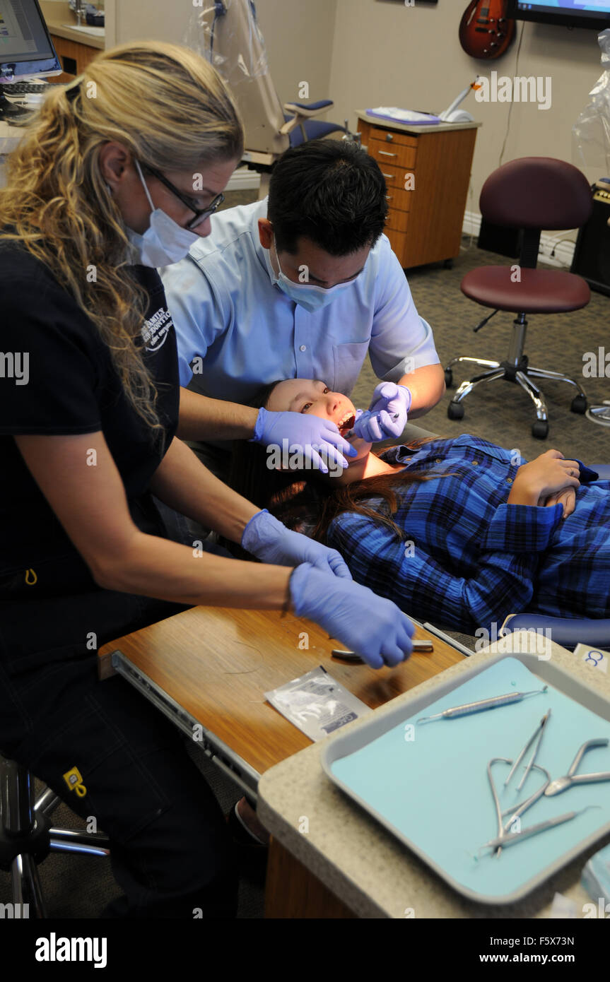 An orthodontist is a type of dentist who specializes in straightening crooked teeth. Here with assistant and patient in office. Stock Photo