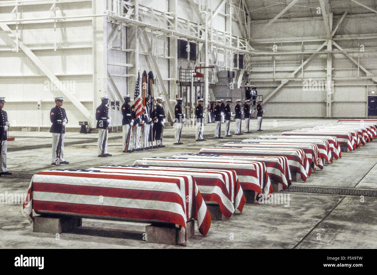 Dover Air Force Base, Delaware, USA 29th October 1983 At precisely 7 A.M., a Marine honor guard and a color guard in ceremonial dress uniforms marched into a huge hangar at the Dover Air Force Base and stood facing 16 coffins. Behind them, suspended from the beams of the hangar, was a 38-foot American flag. The ceremony was the first on American soil honoring servicemen killed in the bombing in Beirut and the invasion of Grenada. Credit: Mark Reinstein Stock Photo