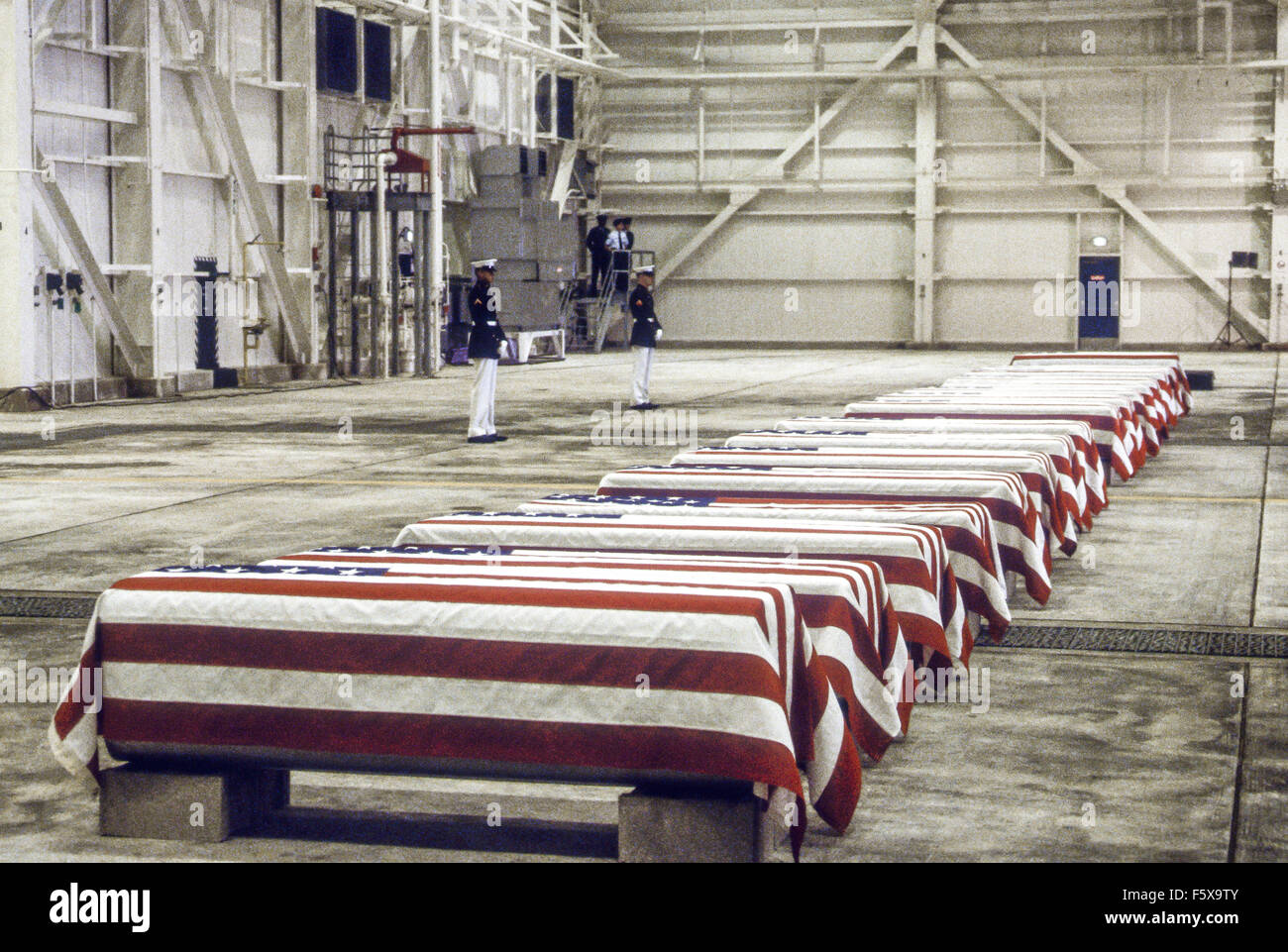 Dover Air Force Base, Delaware. USA 29th October 1983 At precisely 7 A.M., a Marine honor guard and a color guard in ceremonial dress uniforms marched into a huge hangar at the Dover Air Force Base and stood facing 16 coffins. Behind them, suspended from the beams of the hangar, was a 38-foot American flag. The ceremony was the first on American soil honoring servicemen killed in the bombing in Beirut and the invasion of Grenada. Credit: Mark Reinstein Stock Photo