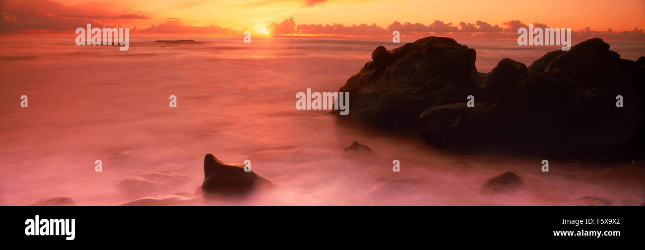 Panoramic scenic of waves painting rocks and sandy shore at sunset in Laguna Beach, California Stock Photo