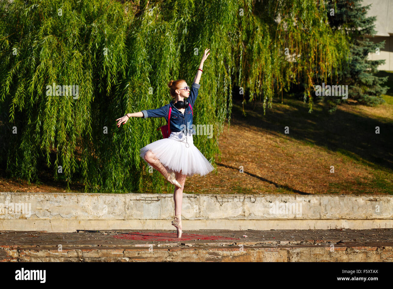 Lovely ballerina dancing hipster in autumn park. Girl listening to music on  headphones. A girl wearing a tutu and sneakers Stock Photo - Alamy