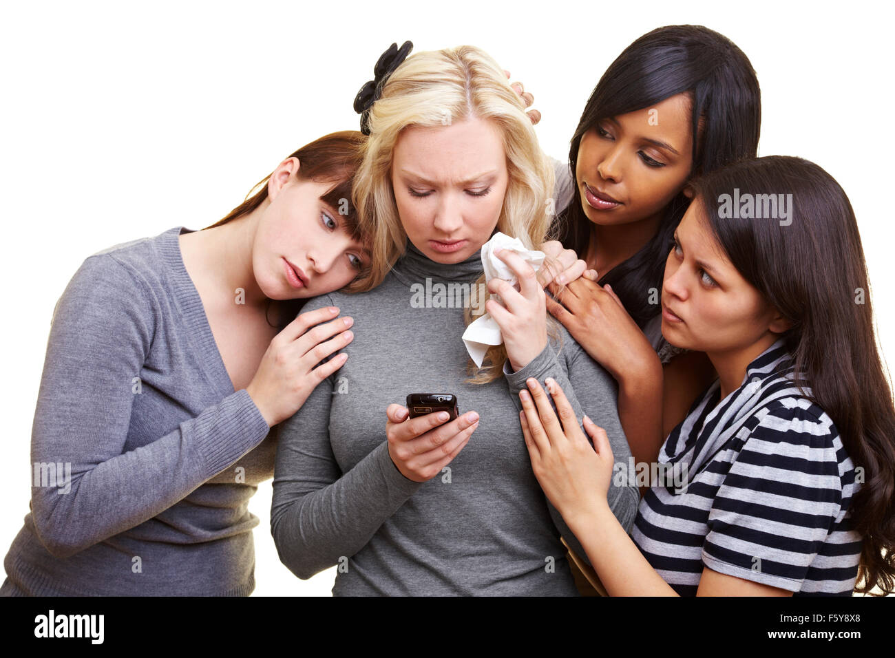 Four young women centered around a cell phone Stock Photo