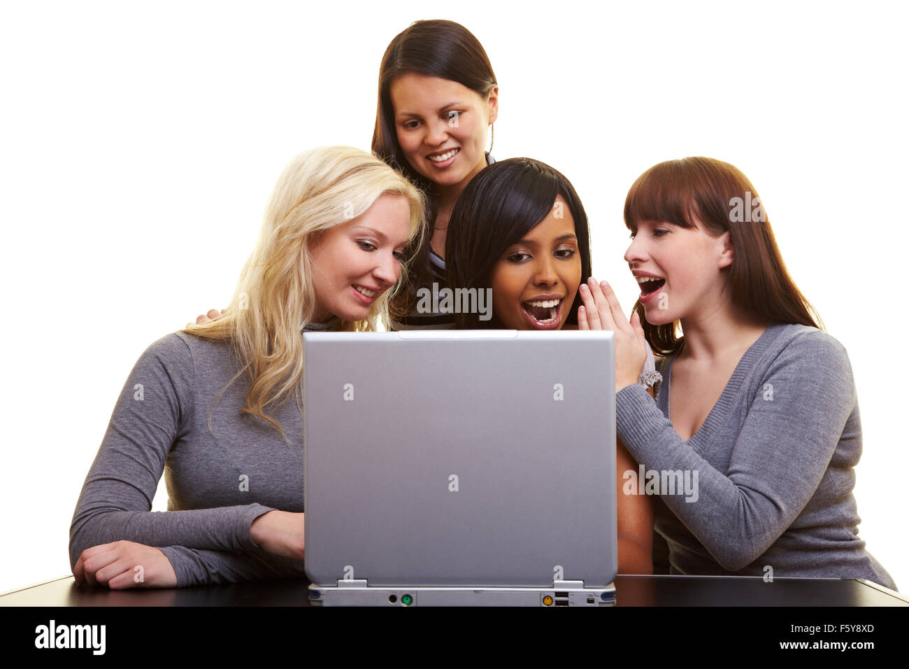 Four young happy woman centered around a laptop Stock Photo