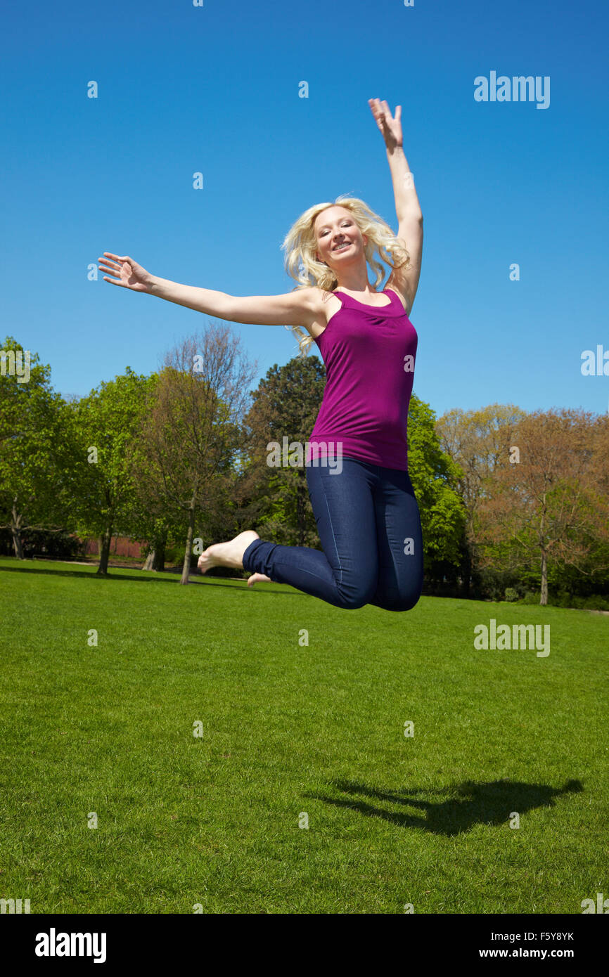 Happy young woman jumping into the air Stock Photo