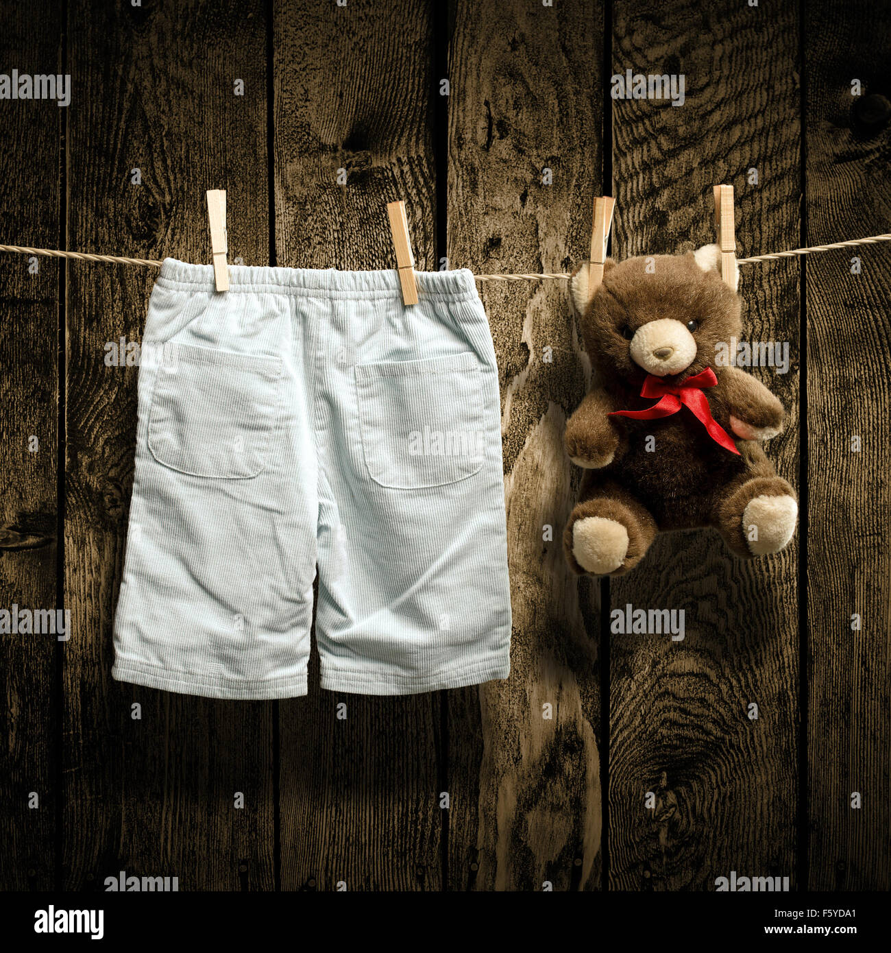 Baby clothes and a teddy bear on clothesline Stock Photo