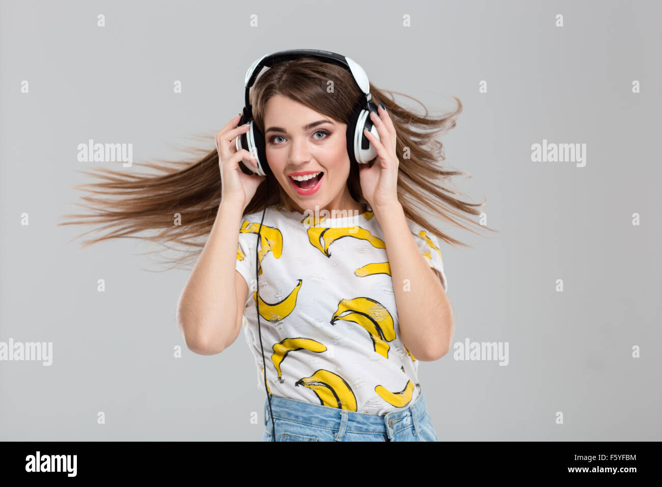 Portrait of a cheerful woman listening music in headphones isolated on ...