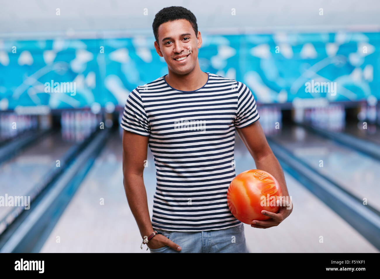 Young smiling man with ball in bowling club Stock Photo