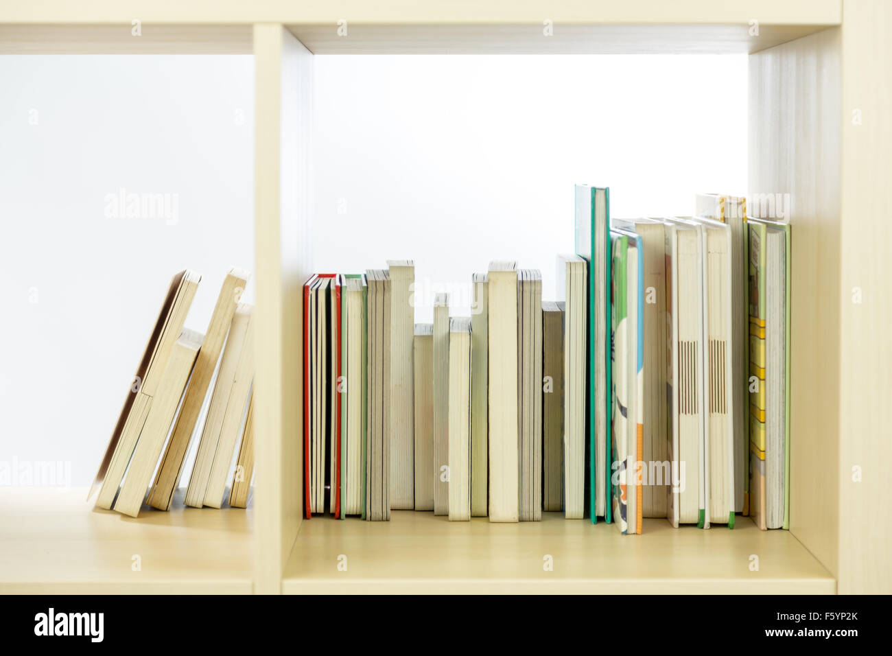 Row of books in a wooden bookcase Stock Photo