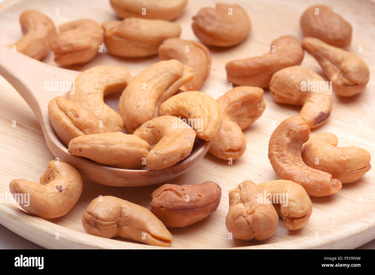 cashew nuts in spoon on wood circle plate Stock Photo