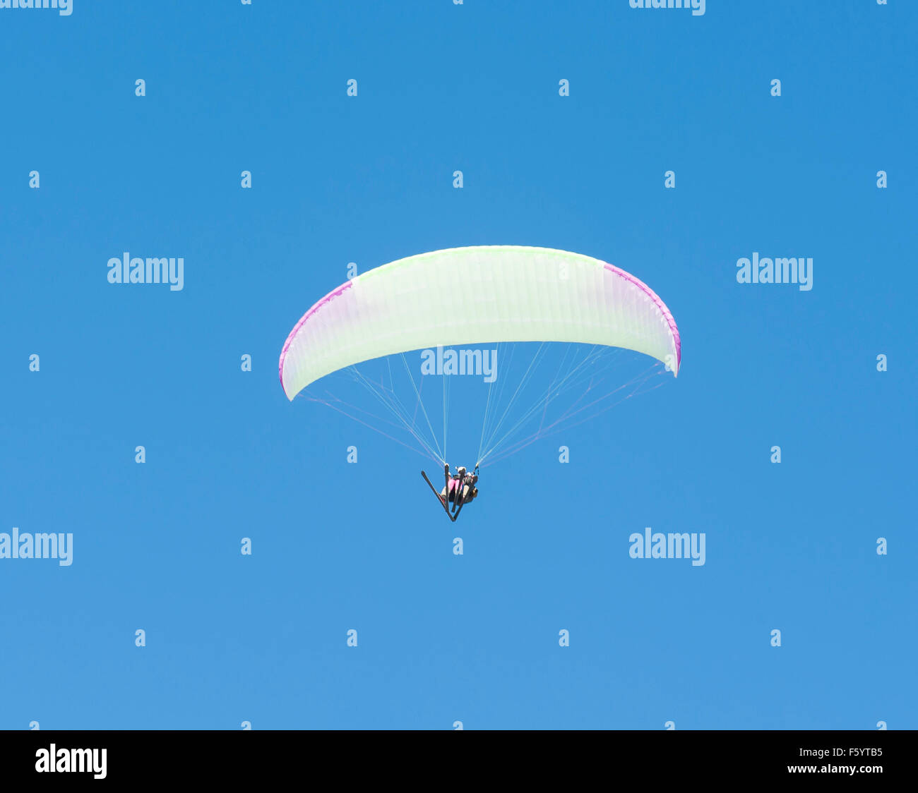 Two people on tandem paragliding flight against blue sky background Stock Photo