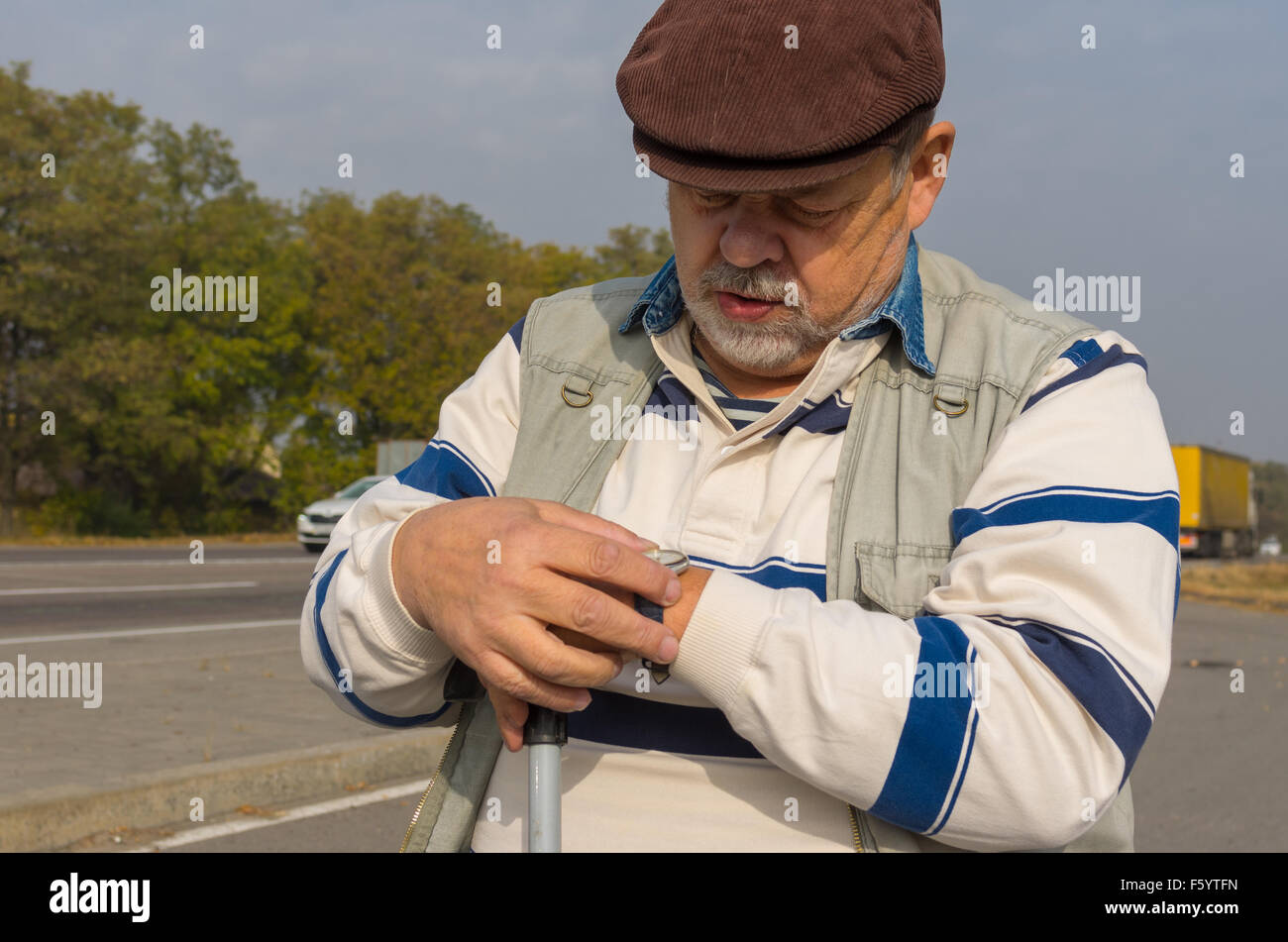 Outdoor portrait of senior man verifying time with wristwatch Stock Photo