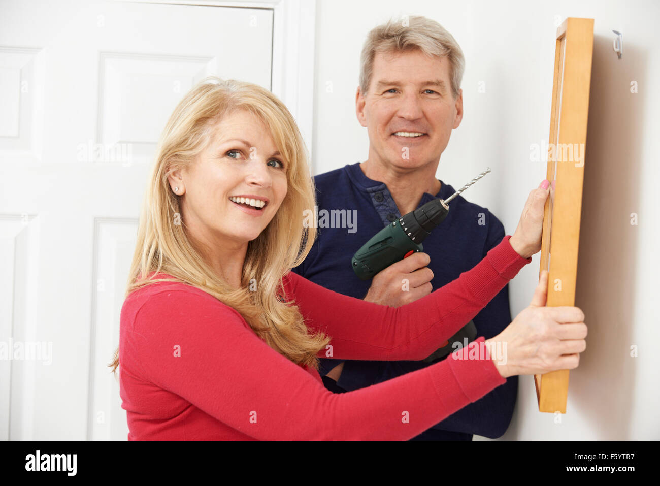 Mature couple hanging picture frame at home Stock Photo