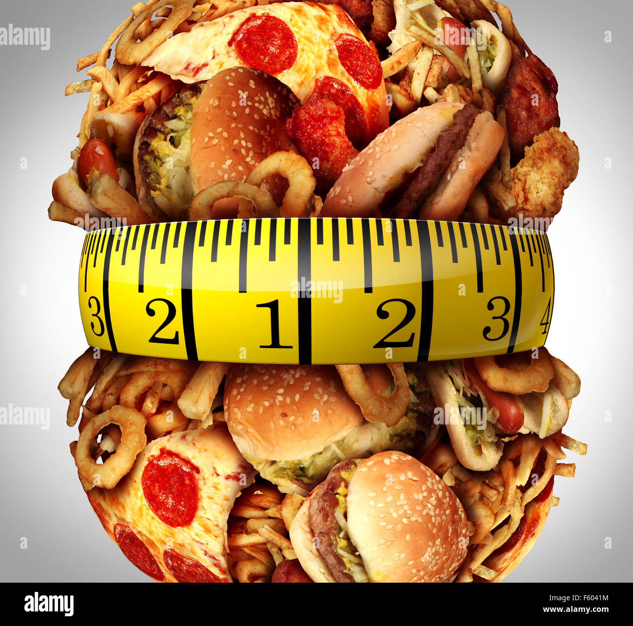 Obesity waistline diet concept as a group of unhealthy fast food as hamburgers,fries and hot dogs bulging out as a fat stomach with a tape measure wrapped around the greasy food. Stock Photo