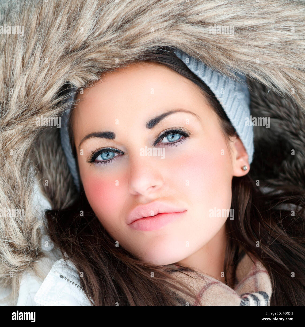 Outdoor beauty portrait of beautiful attractive young woman in warm fur lined hooded winter coat or jacket  Model Release: Yes.  Property release: No. Stock Photo