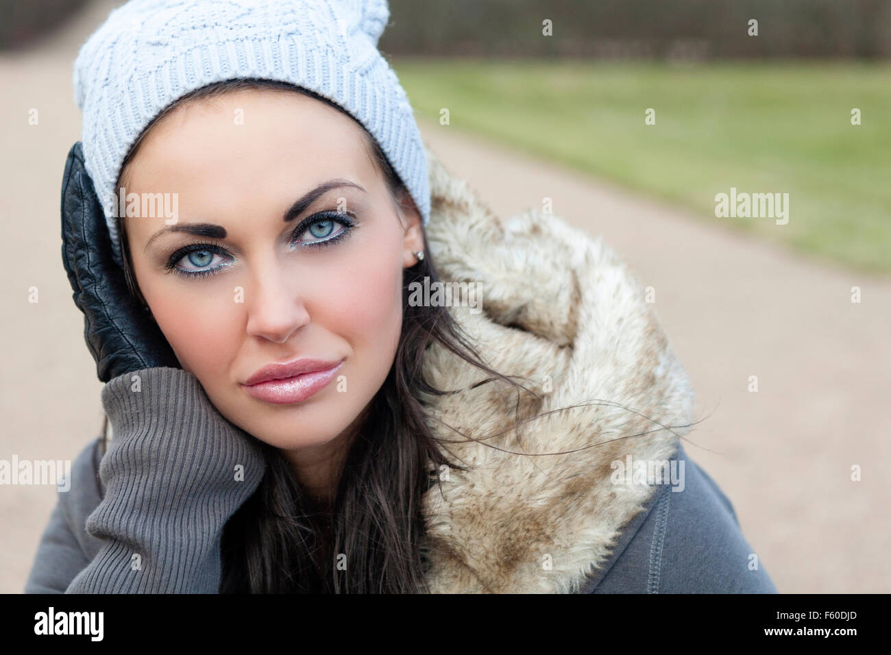 Outdoor portrait of beautiful attractive young brunette woman in warm fur lined winter jacket or coat gloves and hat looking at camera  Model Release: Yes.  Property release: No. Stock Photo