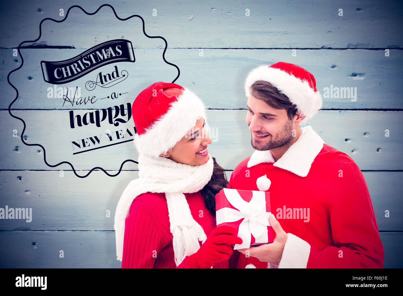 Composite image of festive young couple holding gift Stock Photo