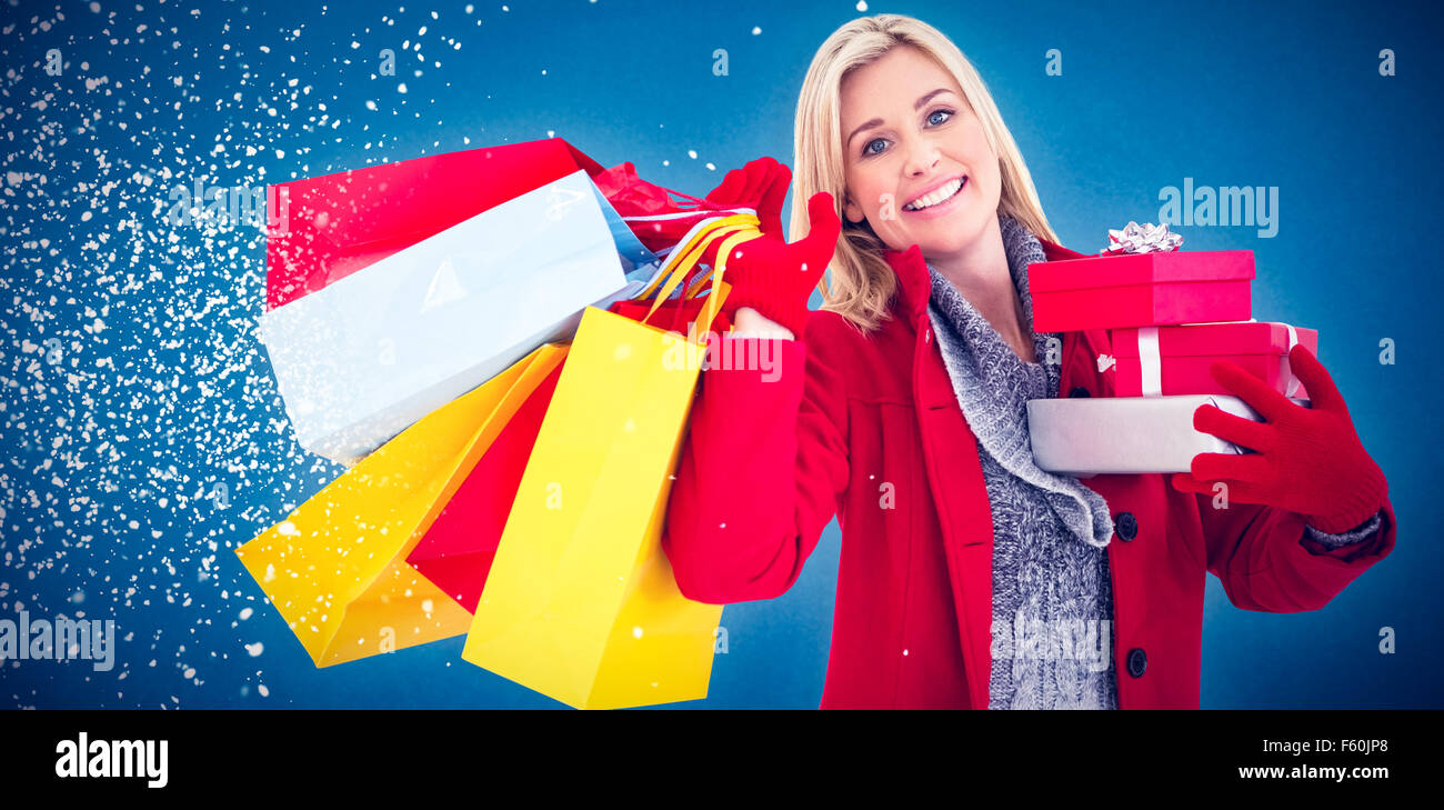 Composite image of festive blonde holding many gifts Stock Photo