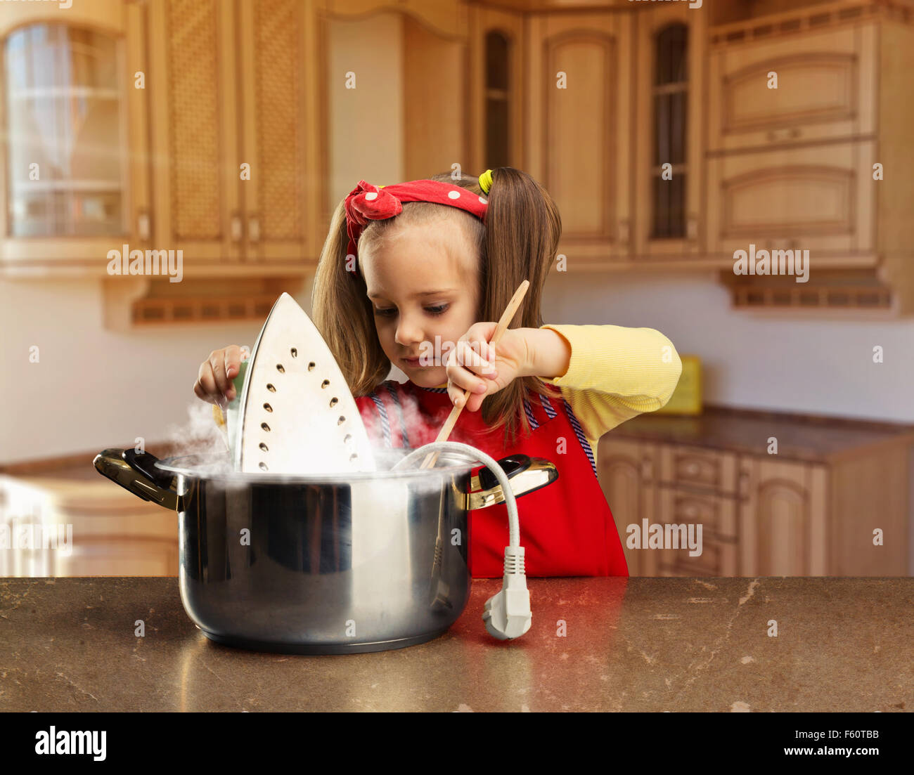 Cute smiling little girl cooking an iron in the pot at home Stock Photo