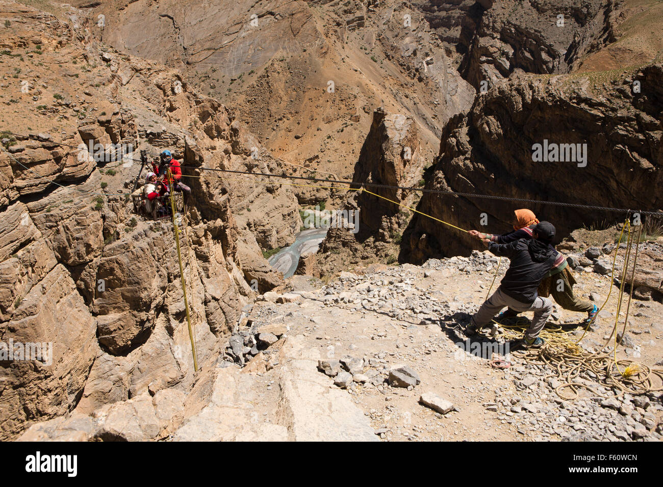 India, Himachal Pradesh, Spiti, Chichim, three women in suspension ropeway basket being pulled over deep gorge to Kibber Stock Photo