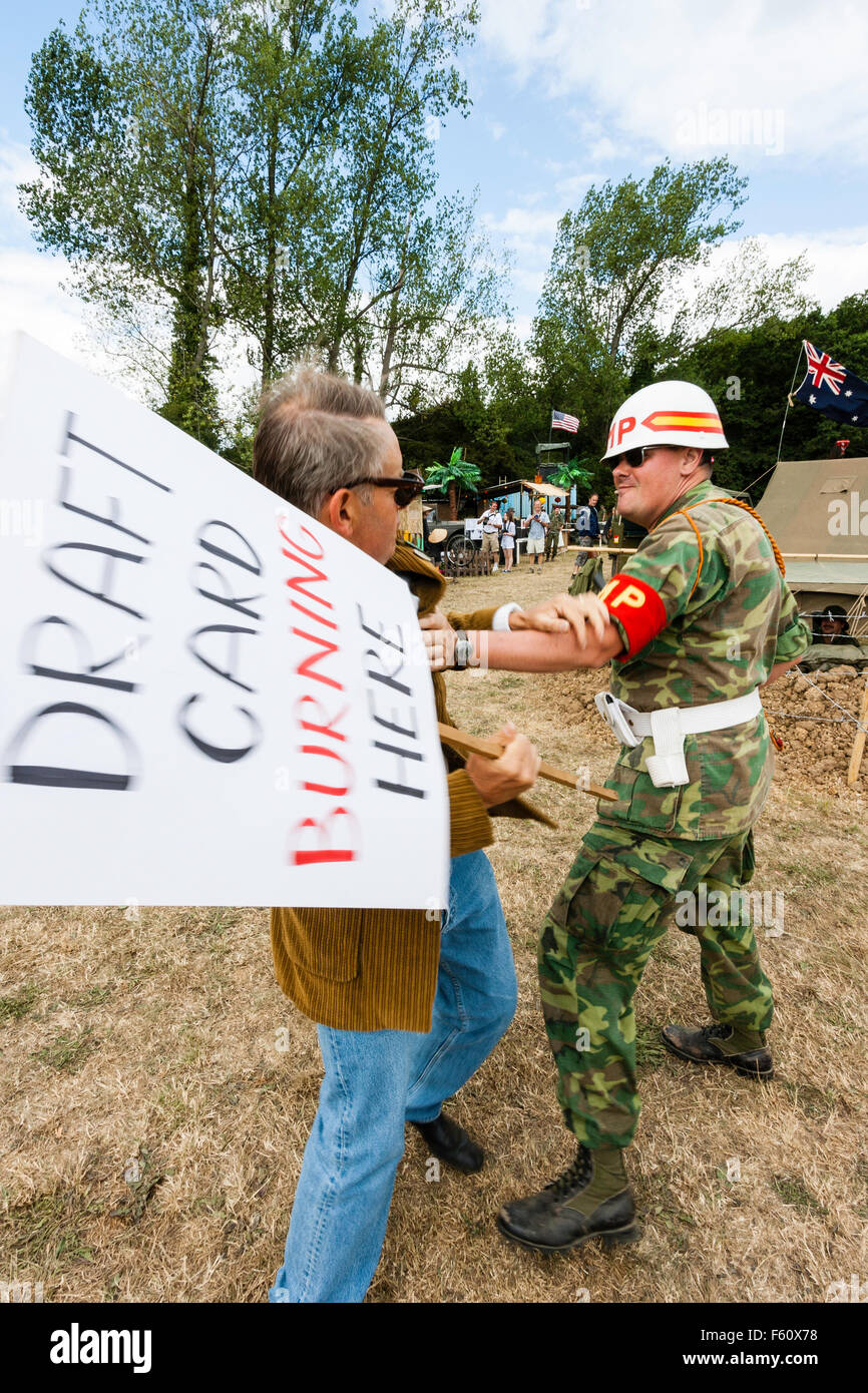Vietnam War Rolling Thunder group reenactment. Lone Peace-movement protester with placard getting violently arrested and struggling with uniformed MP. Stock Photo