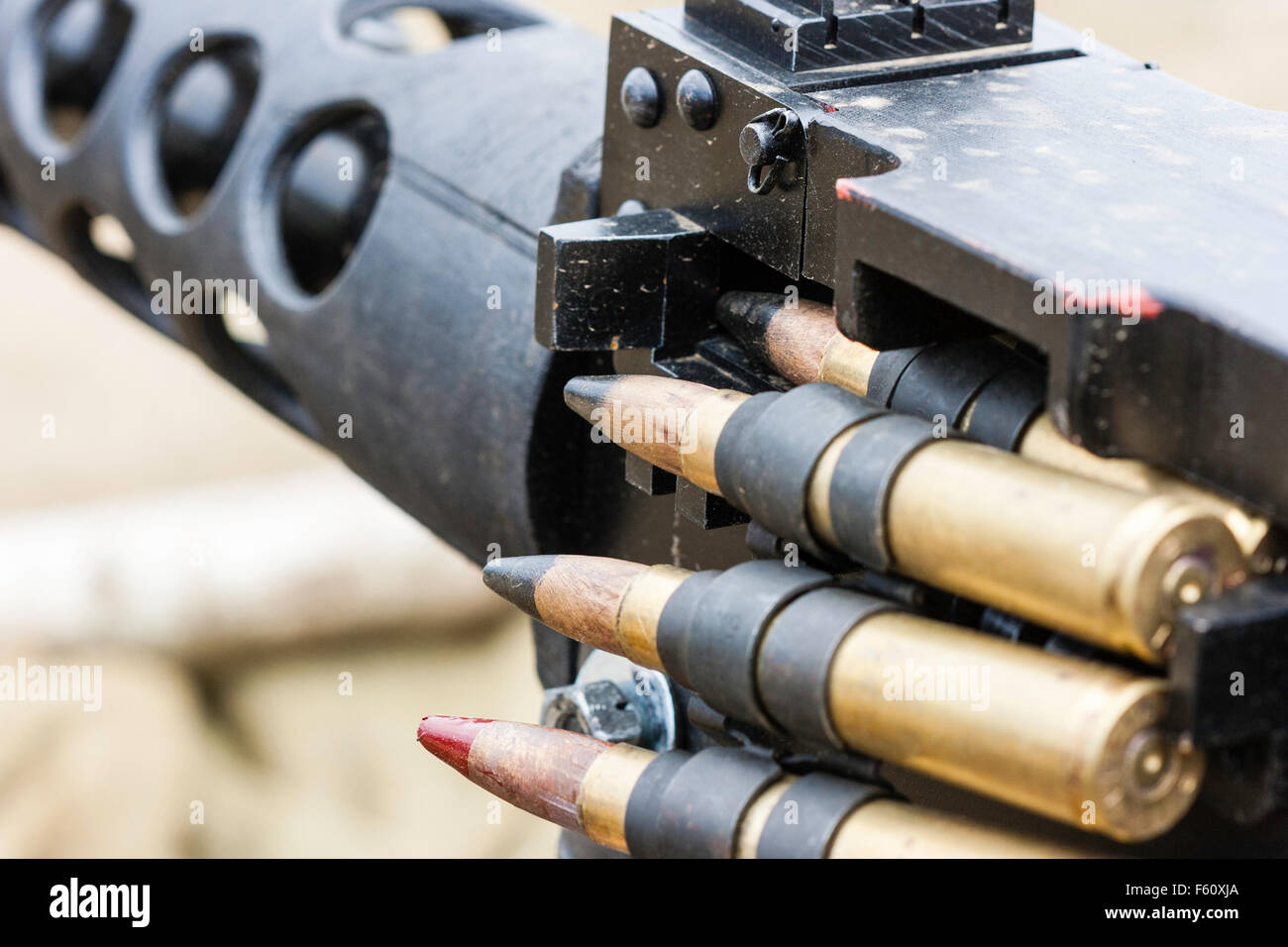 Close up of machine gun ammo belt with bullets in chamber of machine gun and hanging down, one tracer, M20, to every four normal rounds. Stock Photo