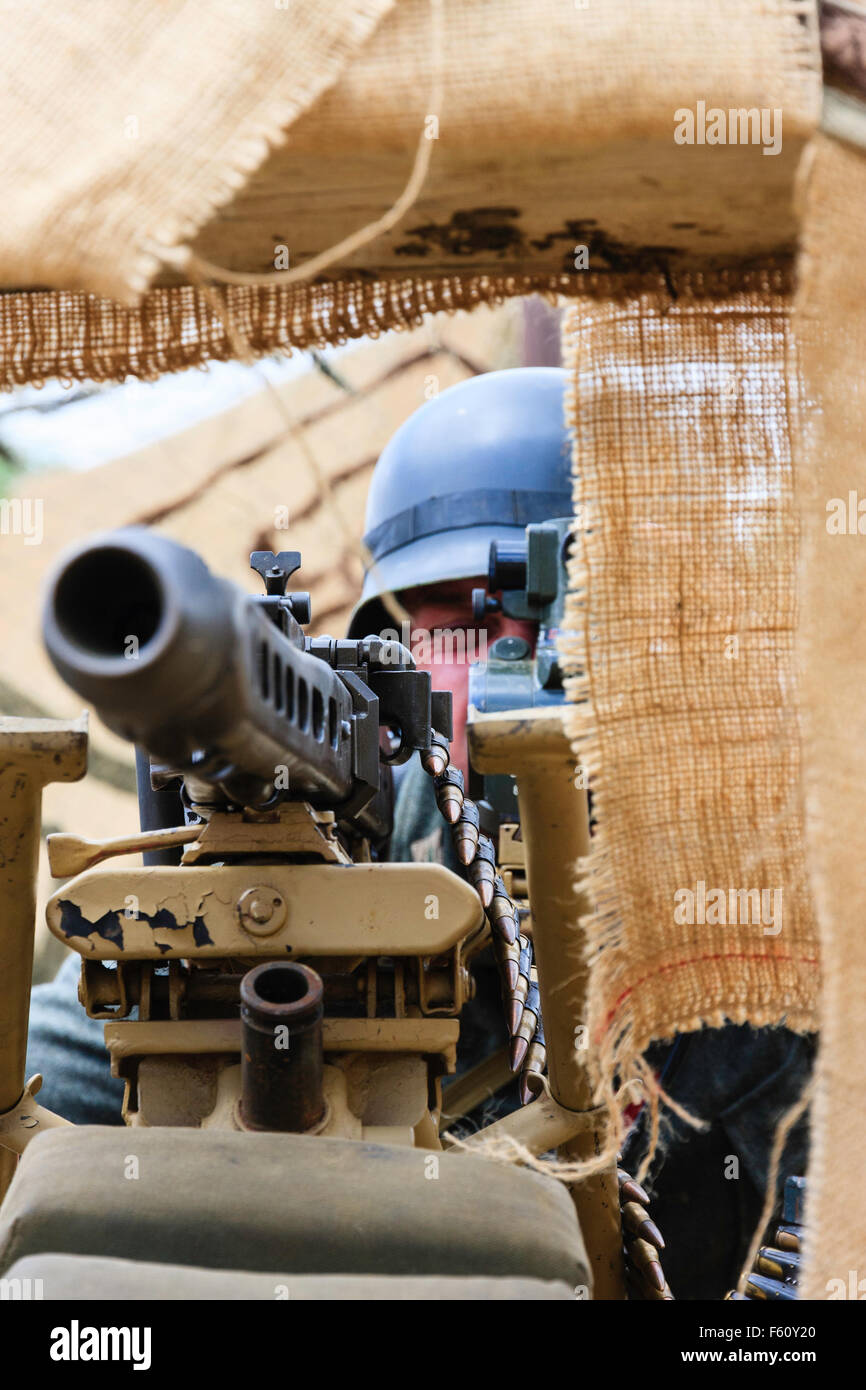 Second world war re-enactment. Close up of German soldier taking aim with heavy machine gun, MG42, in fortified dug-out. Stock Photo