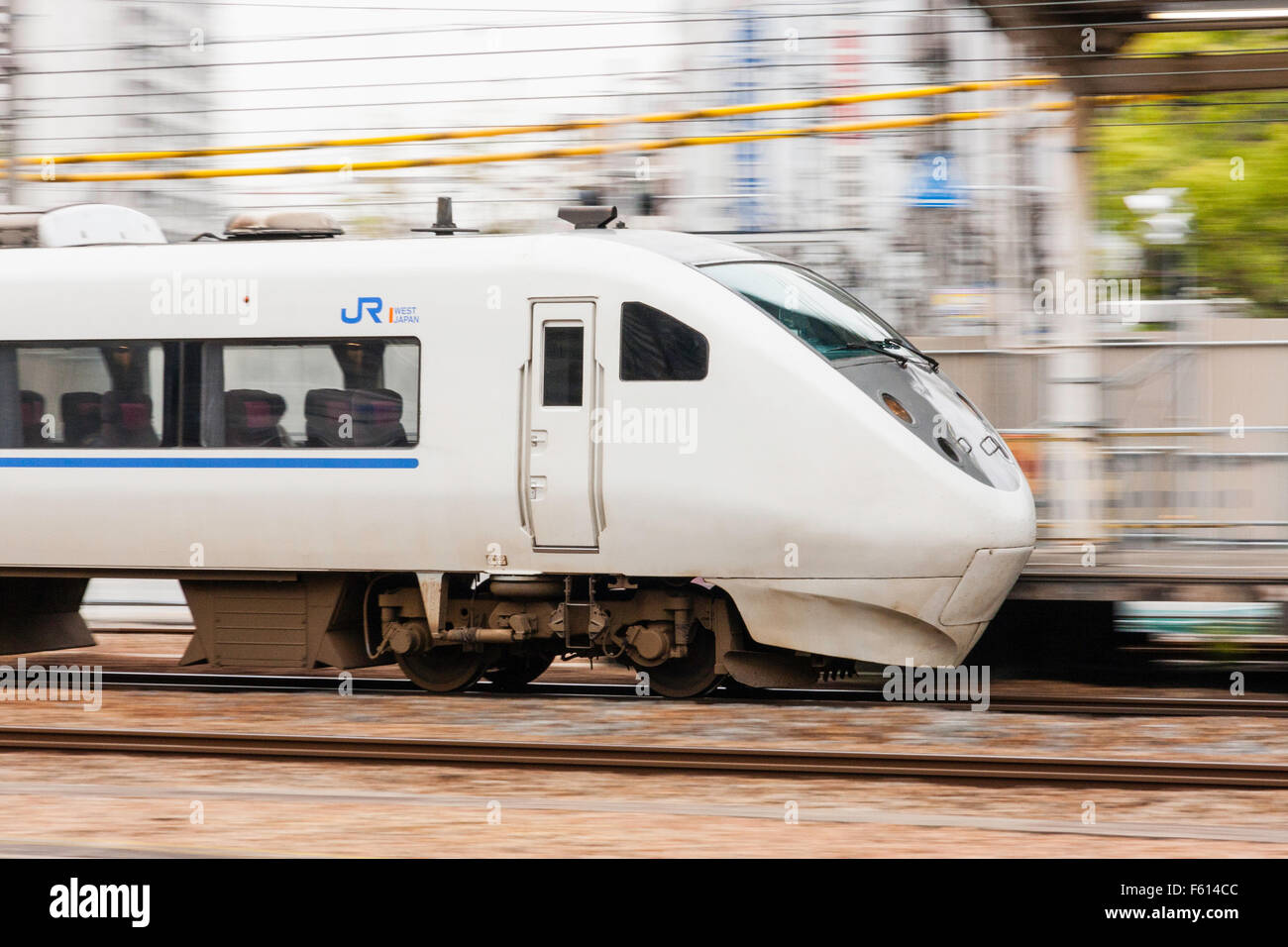 Front of Japanese commuter train passing at speed. Camera panned with train movement, blurred motion background. Stock Photo