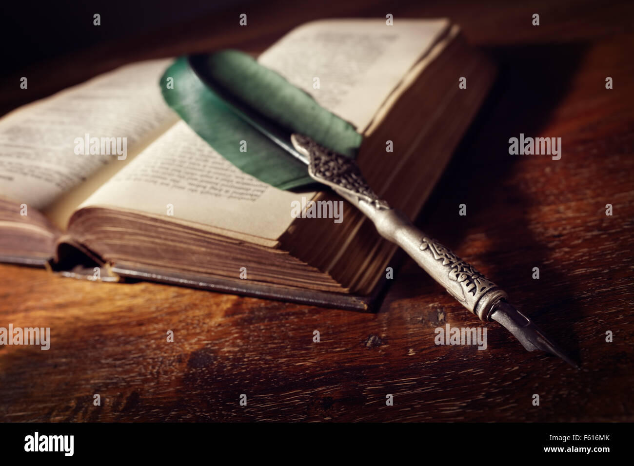 Quill pen resting on an old book on a desk concept for literature, writing, author and history Stock Photo
