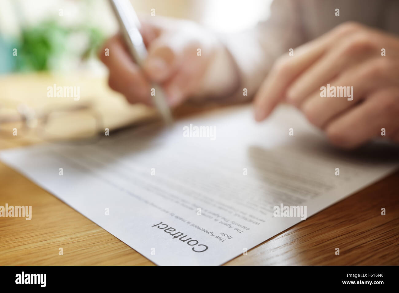 Businessman signing a legal contract document at his office desk Stock Photo