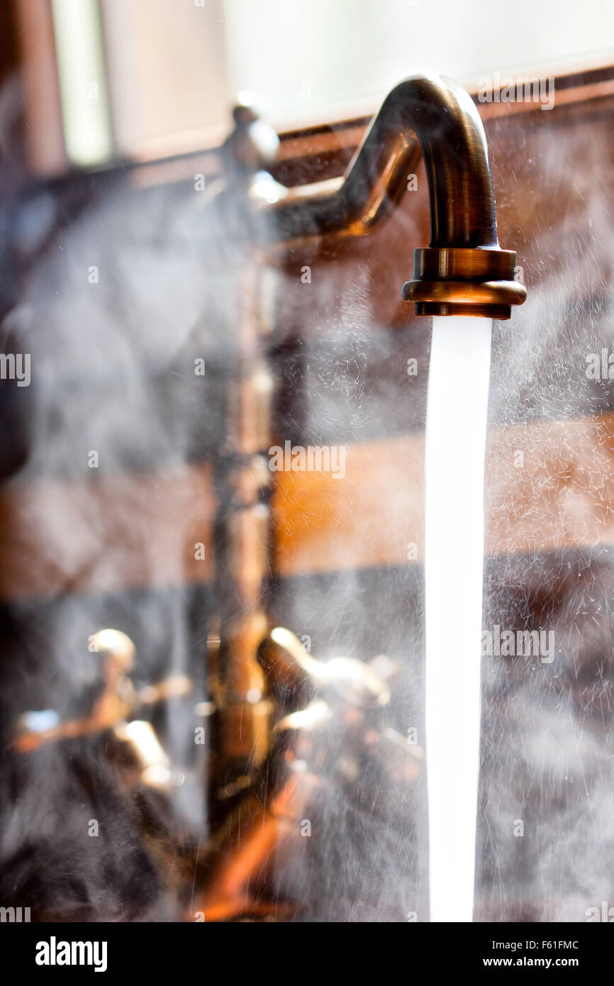 Running vintage faucet with hot water. Close-up view Stock Photo