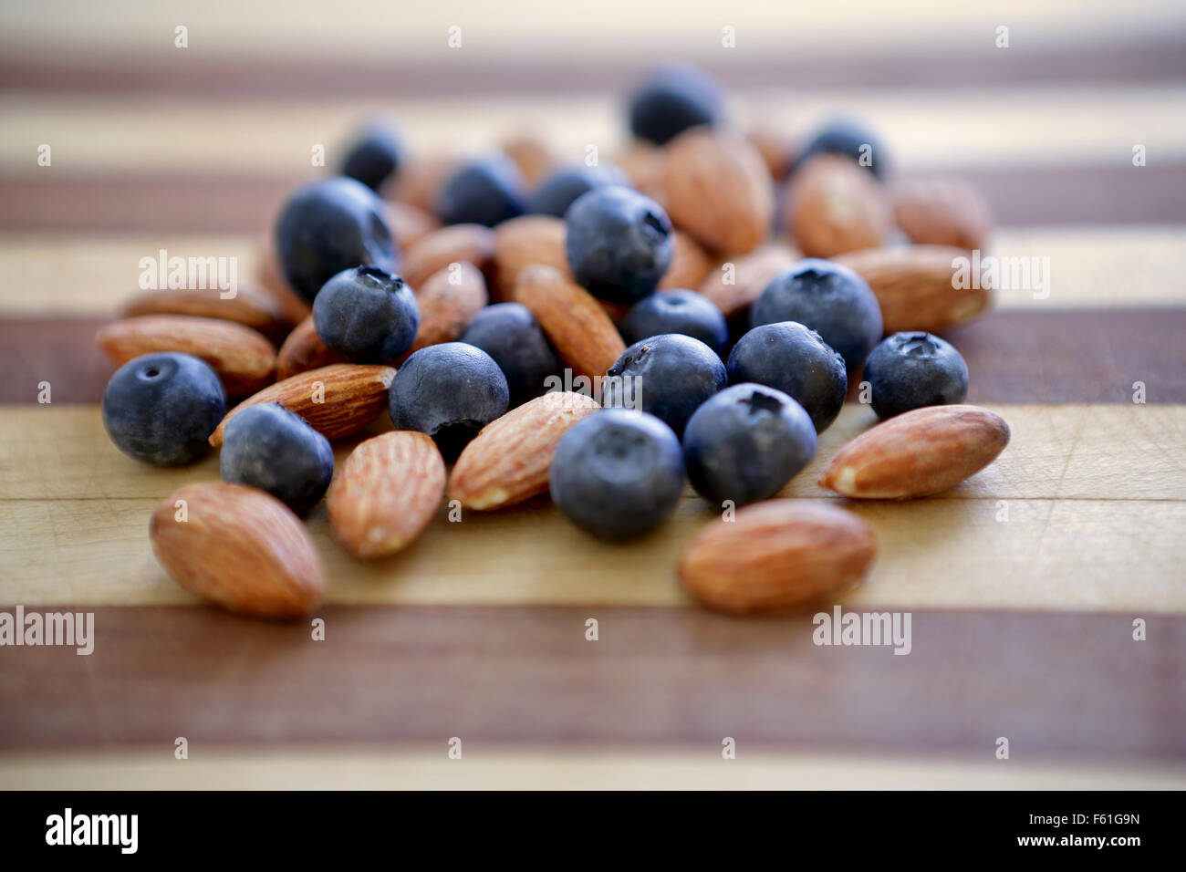 A bunch of almonds and Blueberries on a cutting board ready to