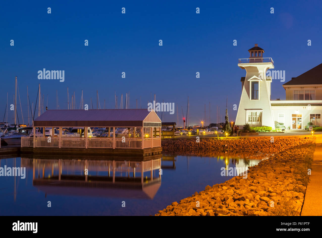 A covered dock and an ornamental lighthouse at the Bronte Outer Harbour Marina at dusk. Bronte, Oakville, Ontario, Canada. Stock Photo