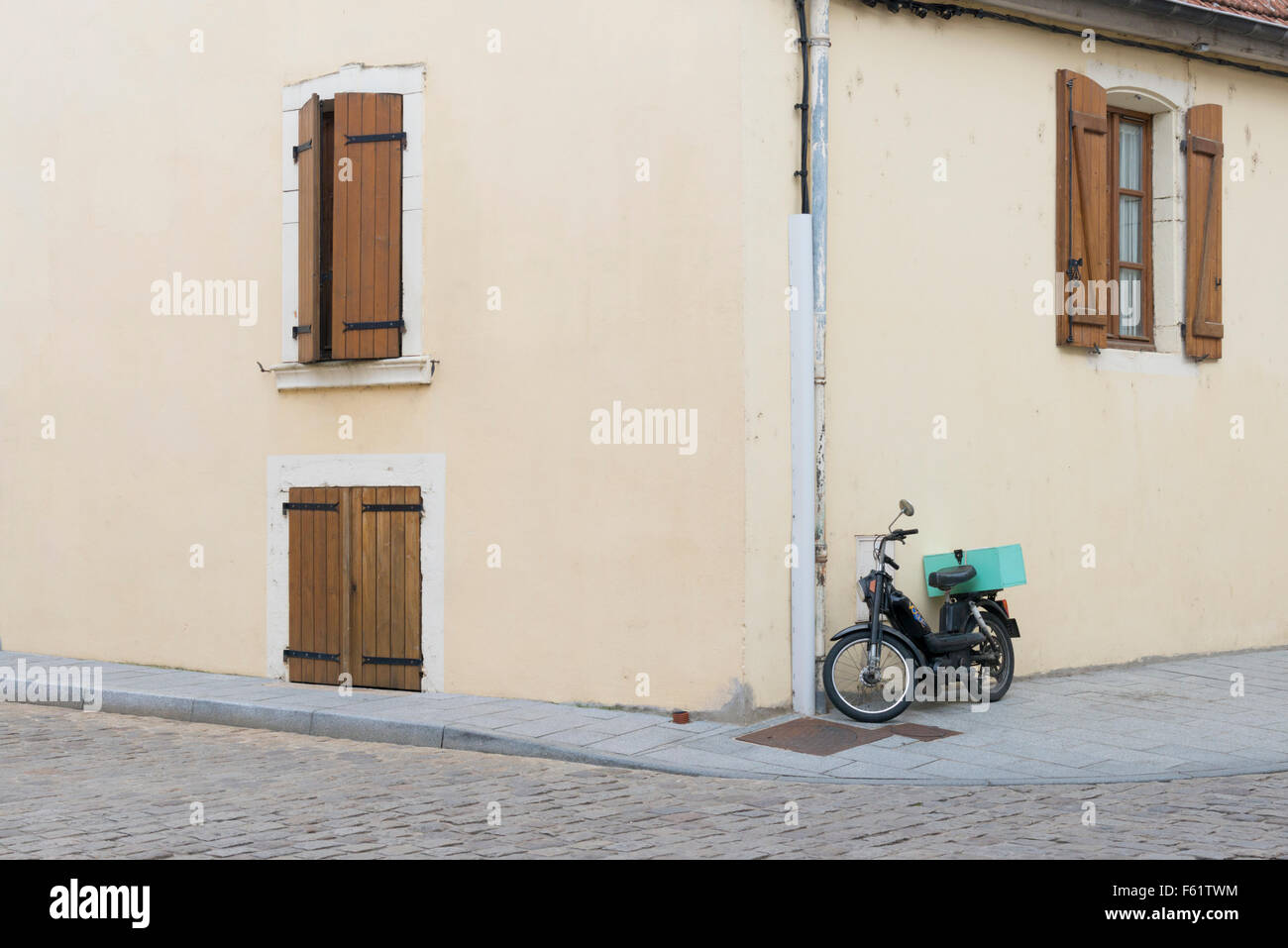 A French street scene in Chagny Burgundy France with a motorcycle parked against a building wall Stock Photo