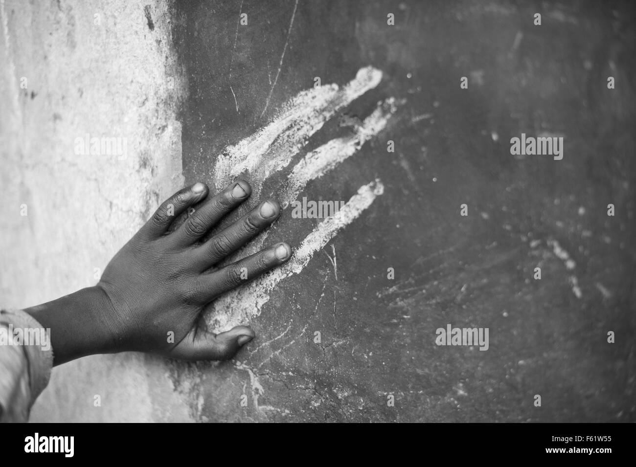 A young boy imitates the traces painted in his hut. Gulu, Northern Uganda. Stock Photo