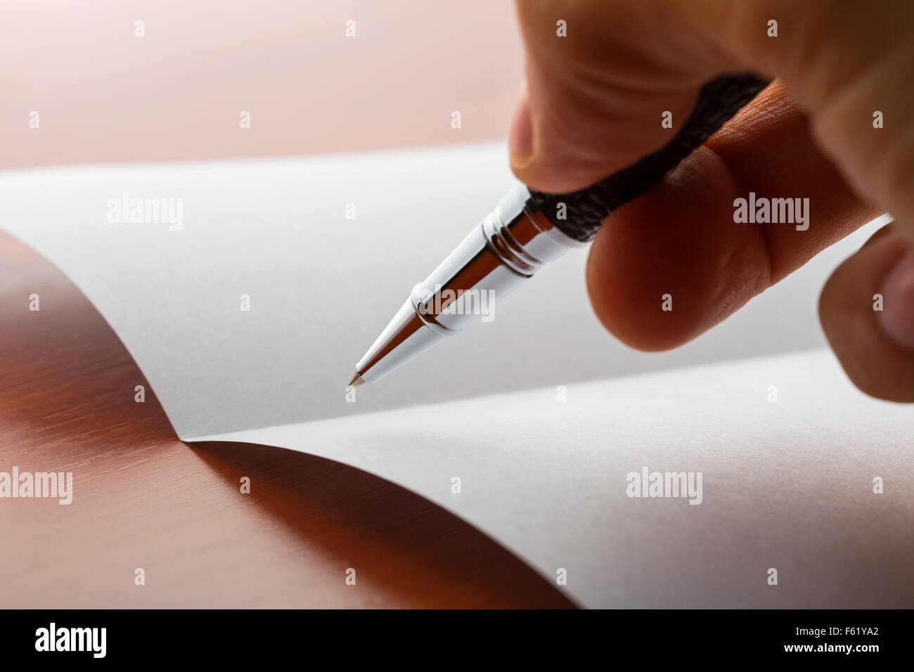 Human hand writing on paper by ball pen on a wooden table Stock Photo