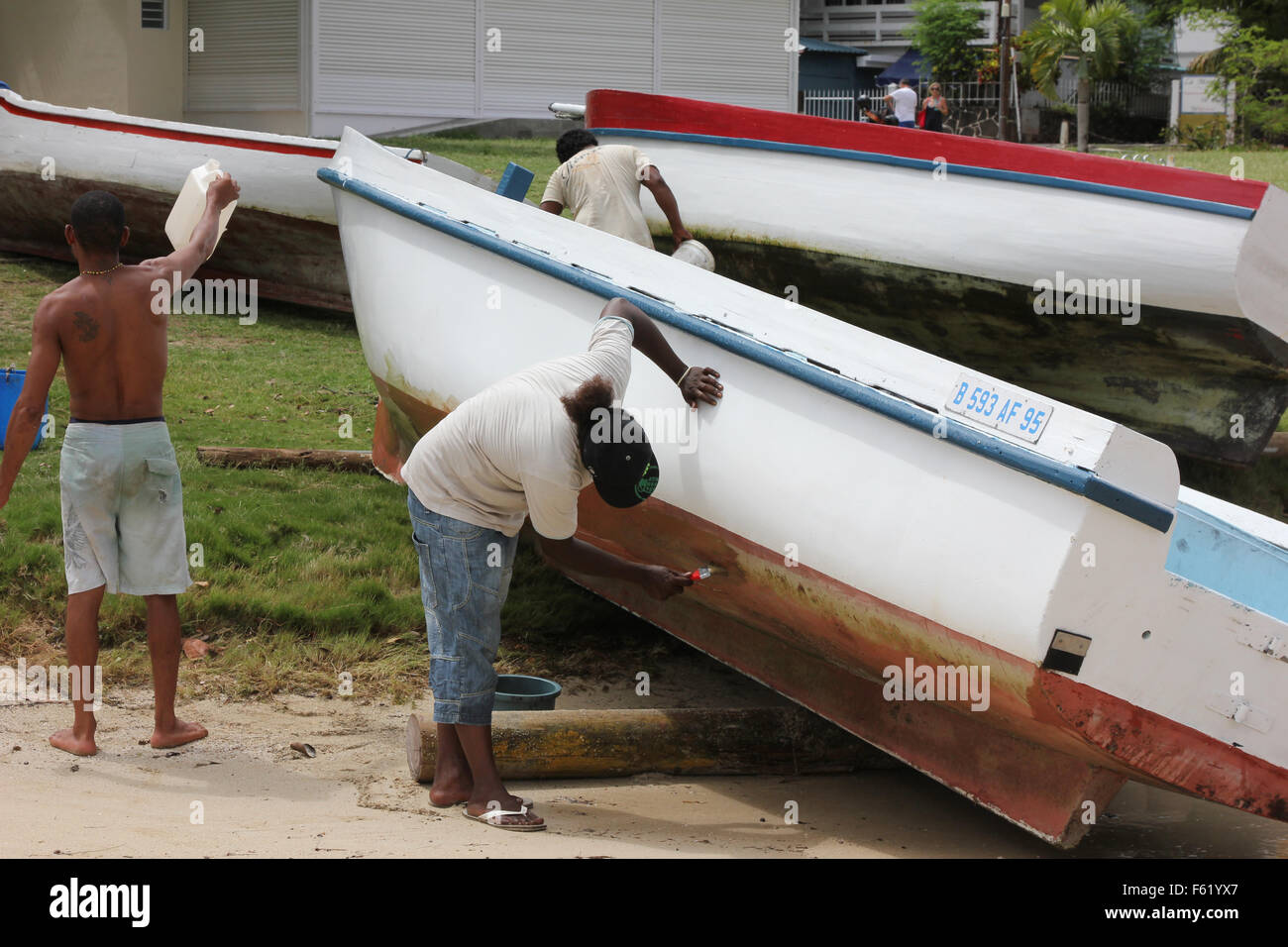 three workers fix the boat on beach Stock Photo