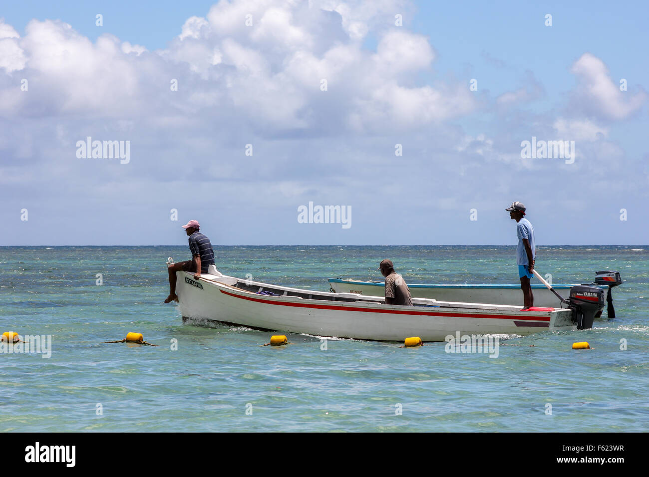 three African men on boat looking at the sea with blue sky background in Mauritius, Africa Stock Photo