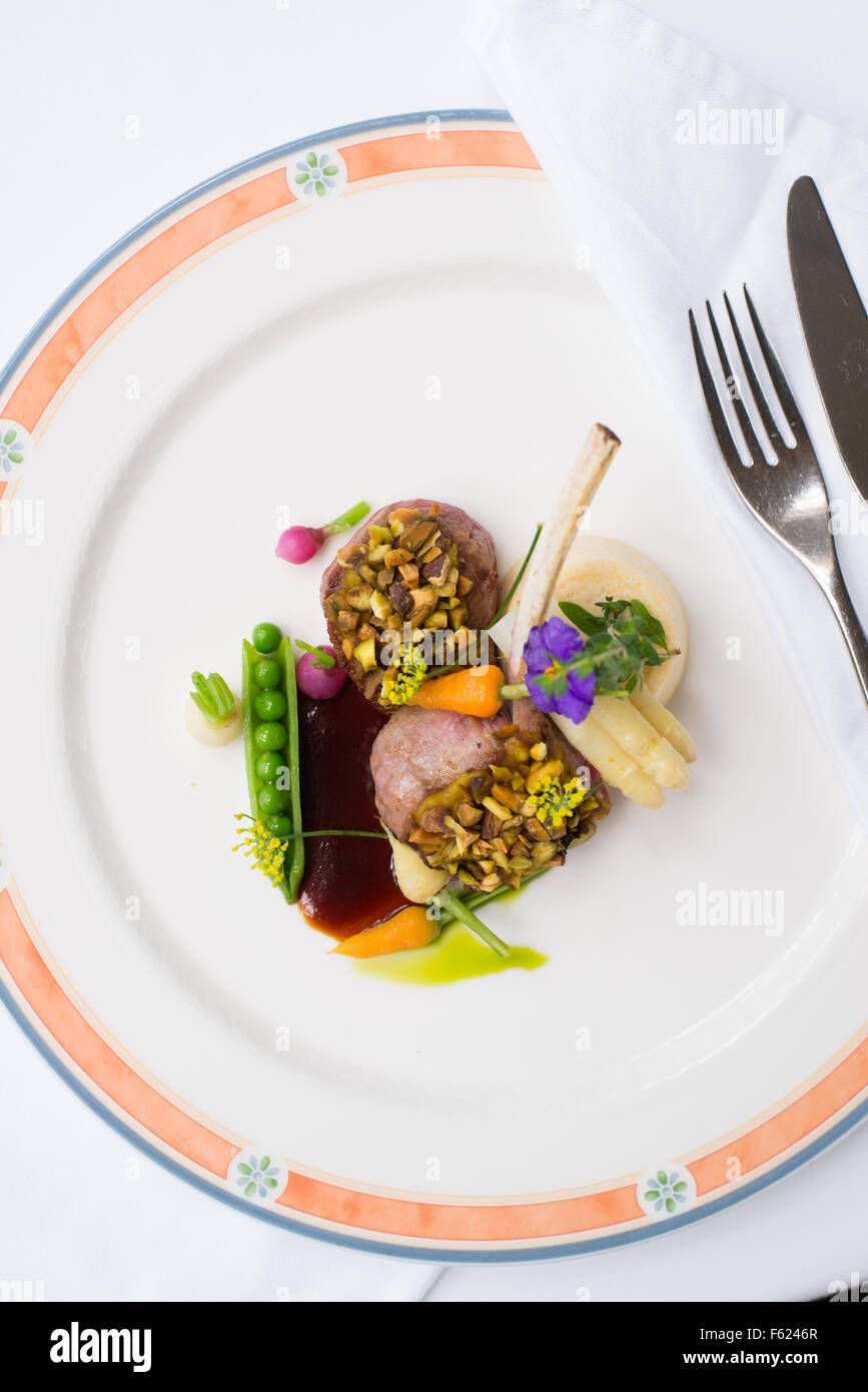 Overhead view of lamb crusted with pistachio, garnished with baby radish and peas. Stock Photo